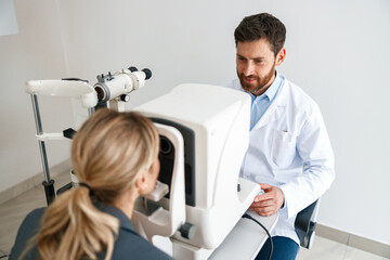 Male ophthalmologist checks a patient's vision at an opticians shop or ophthalmology clinic