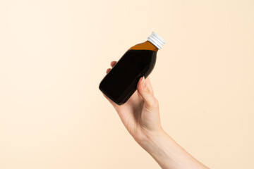 Image of hands with table spoon and bottle of medication. Pouring cough syrup or cold liquid...