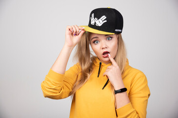 Portrait of young woman in hoodie putting finger in mouth