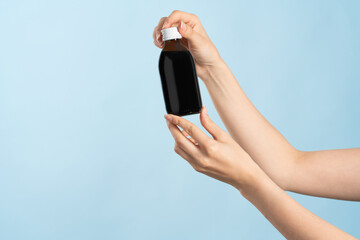 Image of hands holding a brown bottle of liquid cold medication. Bottle without label for product...