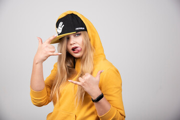Portrait of woman in hoodie showing telephone sign