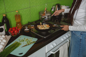 Woman cooking in the kitchen. Preparing healthy food in frying pan. Dieting concept