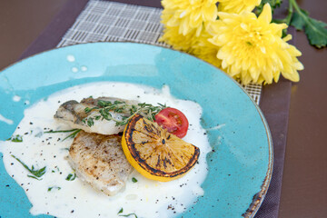 Fried walleye fillet, in creamy sauce with microgreens and lemon