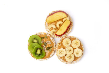 Isolated three rice cake meal with peanut butter, kiwi slice, banana and apple on white background