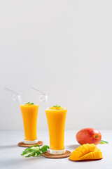 Fresh beautiful delicious mango juice smoothie in glass cup on gray table background.