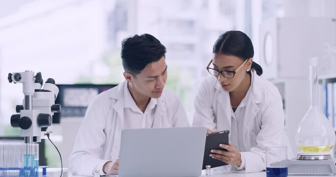 Colleagues discussing forensic research and findings while analyzing medical data. Microbiologists developing innovative ideas with biotechnology. Two scientists working on a digital tablet in a lab