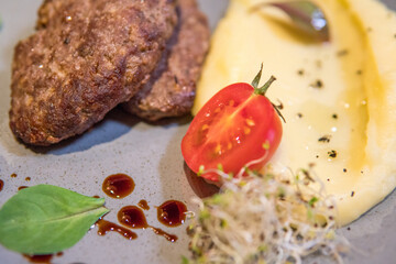 Mashed potatoes with beef patty and tomato