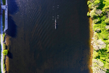 Top down view on a rowing team in a small river. Water sport and workout concept.