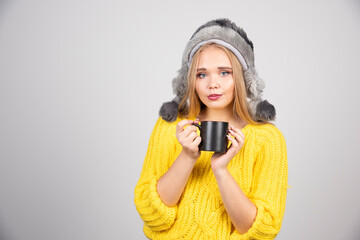 Blonde woman in yellow sweater holding cup of tea