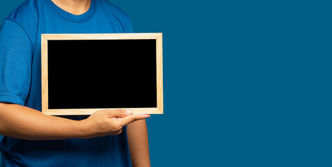 Close-up of hand holding a blank mini blackboard while standing on a blue background