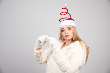 Woman in Santa hat acts surprised on gray background
