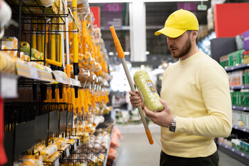 a man in a construction hypermarket chooses a roller for painting work