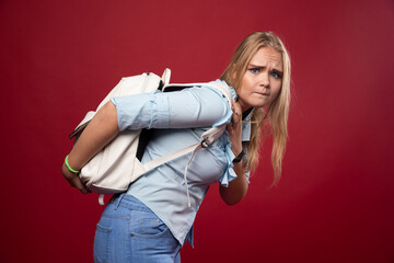 Blonde schoolgirl carrying a heavy backpack