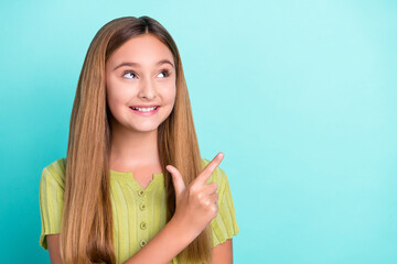 Photo of cheerful nice girl toothy smile look direct finger empty space isolated on vibrant teal color background