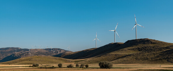 clean electricity producing wind turbine or windmill built on a windy mountain ridge