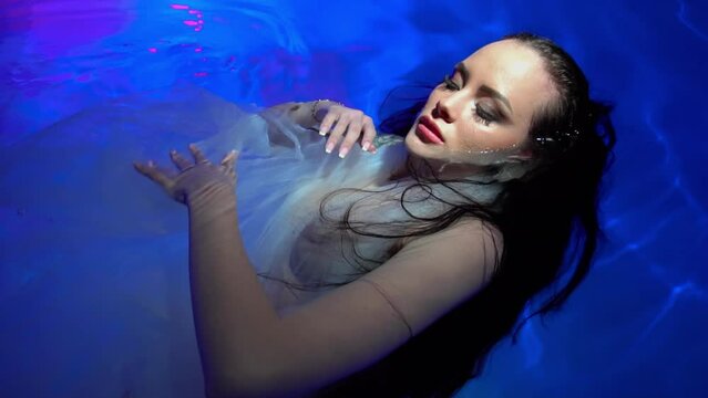 Slow Motion Beautiful woman swimming underwater with elegant dress