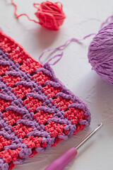 Pink purple seamless knitted texture. Volumetric crochet striped pattern. Crochet process.