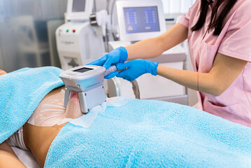 Beautician therapist applying cryolipolysis treatment in beauty salon.	