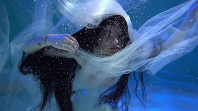Elegant girl dancer in white dress in a state of levitation under the deep water