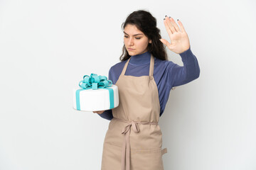 Pastry Russian chef holding a big cake isolated on white background making stop gesture and disappointed