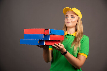 Deliverywoman in uniform holding cardboards of pizza