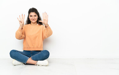 Teenager Russian girl sitting on the floor counting nine with fingers
