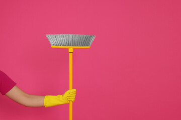 Woman holding broom on pink background, closeup. Space for text