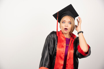 Female student in gown looking surprised on white background