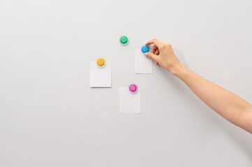 Image of white board and hand attaching pieces of paper to the magnetic board.