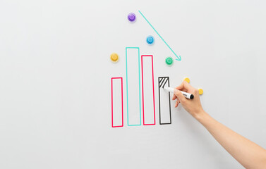 Image of white magnetic board  with bussines chart report. Woman's hand showing ups and downs on...