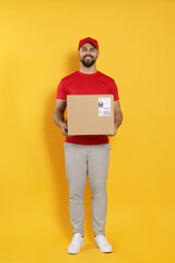 Courier holding cardboard box on yellow background