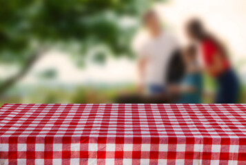 Table with checkered picnic cloth outdoors on sunny day. Space for design