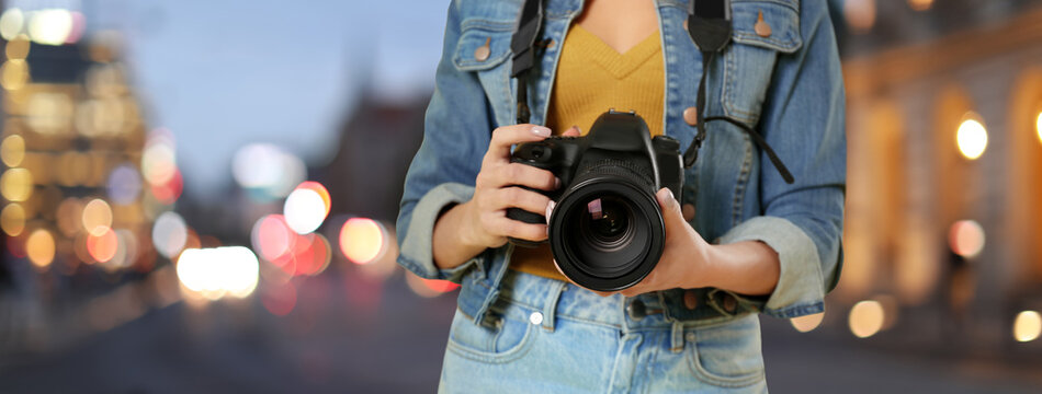Professional photographer with modern camera and blurred view of beautiful city in evening. Banner design