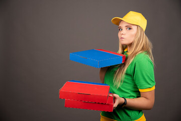 Deliverywoman in uniform holding cardboards of pizza