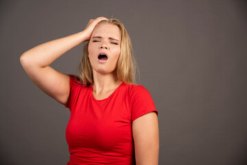 Portrait of tired woman touching her head over dark background