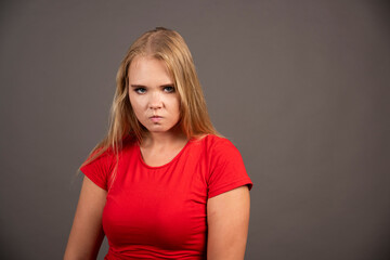 Young woman in red shirt posing on dark background