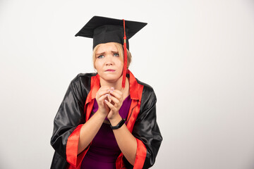 Female graduate student in gown standing on white background