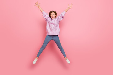 Photo of cute excited girl knitwear sweater jumping high like star isolated pink color background