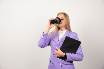 Woman drinking black cup of coffee and holding a tablet on white background