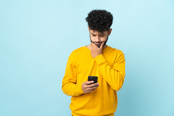 Young Moroccan man isolated on blue background thinking and sending a message