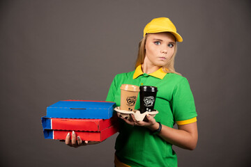 Deliverywoman holding cups of coffee and cardboards of pizza