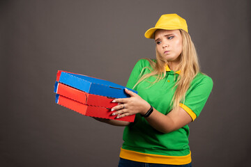 Deliverywoman in uniform holding cardboards of pizza