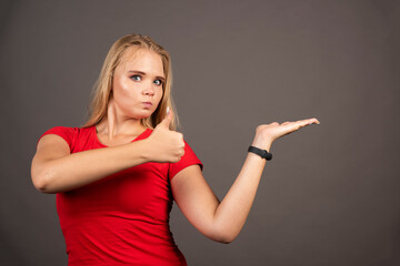 Young woman showing thumb up on dark background