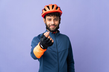 Young Moroccan cyclist man isolated on purple background making money gesture