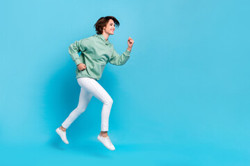 Fototapeta na wymiar Photo of pretty adorable woman wear green sweatshirt running fast empty space isolated blue color background