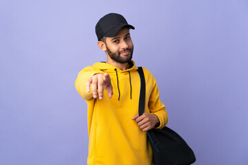 Young sport Moroccan man with sport bag isolated on purple background pointing front with happy expression