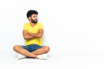Fototapeta premium Young Moroccan handsome man sitting on the floor over isolated background making doubts gesture while lifting the shoulders