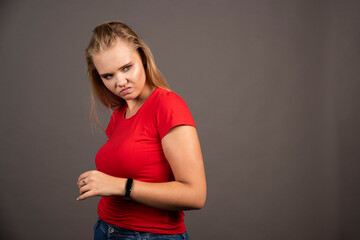 Upset young woman in red shirt on dark background