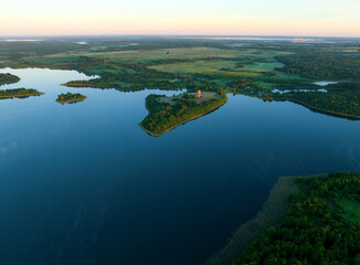 Lake in rural, aerial view. Freshwater Lakes. Abandoned Trinity Church in village of Belaya Tserkov. Lake Chereiskoye in Chereya village. Lighthouse on island. Panoramic landscape view of river.