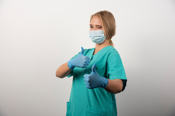 Female doctor showing thumb up and wearing a medical mask